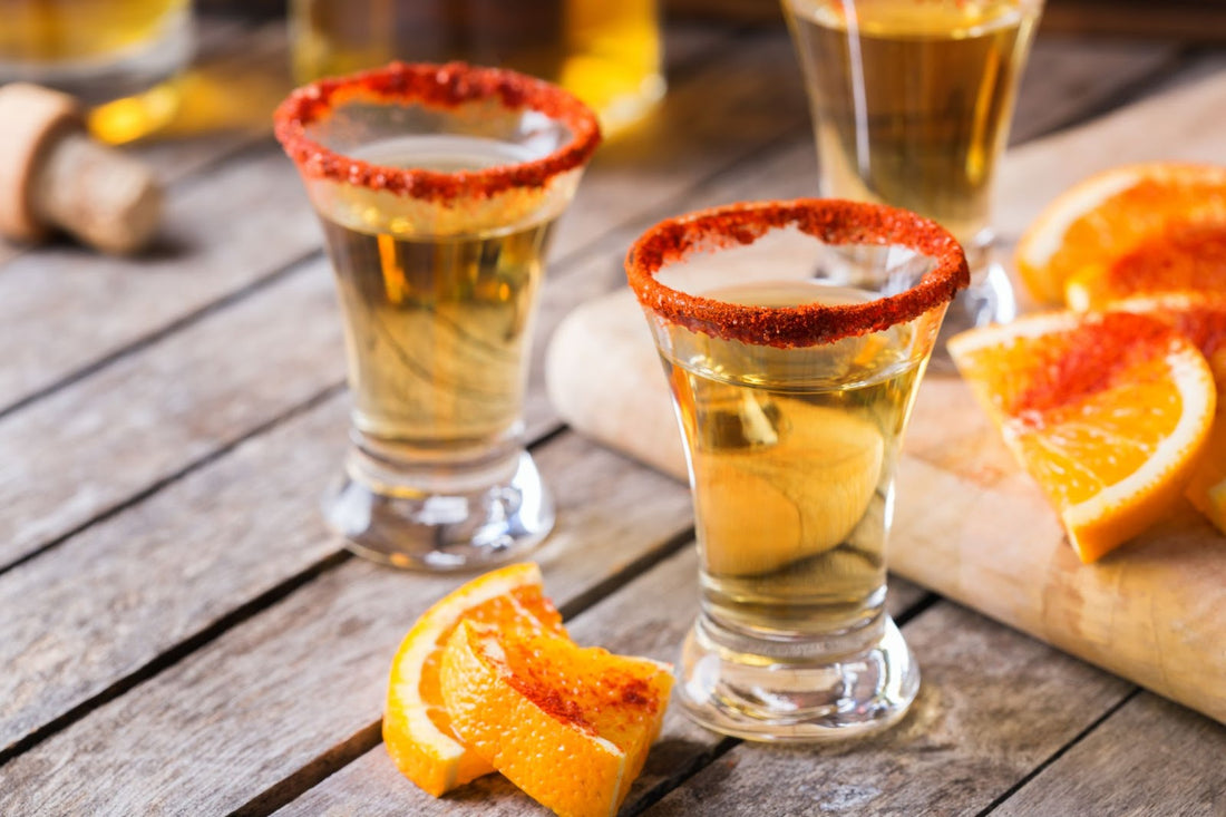 A close-up shot of Mexican mezcal or mescal shot with chili pepper and orange.